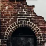 Cozy rustic fireplace with exposed bricks and menu board in a restaurant setting.